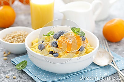 Corn porridge with fresh blueberry, orange and pine nuts in bowl served for breakfast Stock Photo