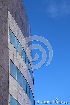 The corner of a modern curved office building against a blue sky Stock Photo