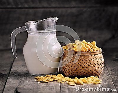 Cornflakes in basket and glass of milk on wooden table Stock Photo