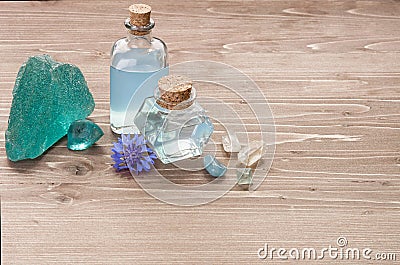 Cornflower flower blue water in glass bottles, natural stones and flowers on brown wooden background, copy space. Aromatherapy or Stock Photo