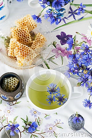 Cornflower herbal tea in white cup on white crochet napkin intdoors, healthy cornflower drink with honey Stock Photo