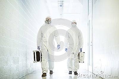 Corona virus concept. Two male scientist doctors in biochemical protective suits walk in laboratory coridor with Stock Photo