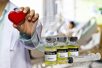 Coronavirus Covid-19 Vaccine in bottle and syringe for against virus with doctor holding red heart in hand on blur image Stock Photo