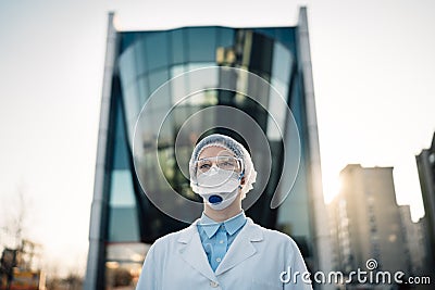 Coronavirus doctor standing in front of modern clinic building,working in the isolation ward.Medical professional in protective Stock Photo