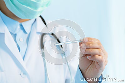 Coronavirus stop infection. young female doctor wearing mask with thermometer and stethoscope against infectious diseases and flu Stock Photo