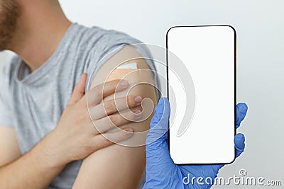 Coronavirus Vaccination digital passport. Hand in medical glove holding phone with empty screen Stock Photo