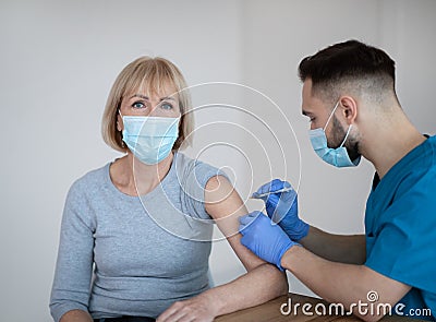 Coronavirus vaccination for seniors. Mature woman being immunized against covid-19 at clinic during her visit to doctor Stock Photo