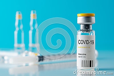 Coronavirus vaccine vial glass with a syringe on blue background. Covid-19 medicine vaccination concept. World pandemic concept Stock Photo