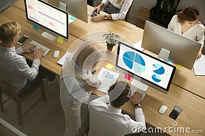 Corporate employees working on computers in office together, top Stock Photo