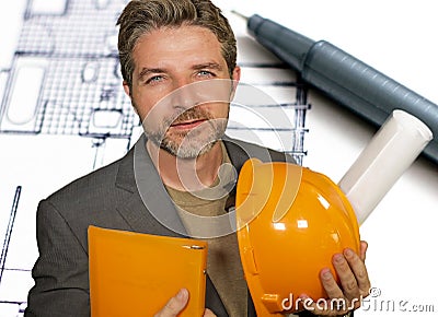 Corporate portrait of attractive efficient and confident architect man holding builder helmet and building construction blueprints Stock Photo