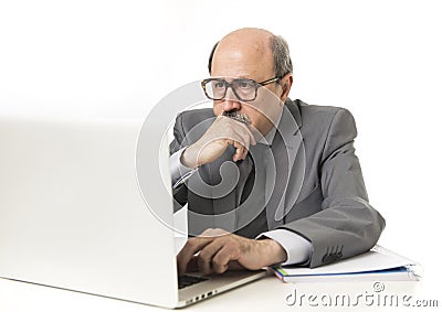 Corporate portrait bald 60s serious and bossy business man thinking and working at computer laptop office desk Stock Photo