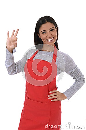 Corporate portrait of young attractive hispanic home cook woman in red apron posing happy and smiling isolated Stock Photo