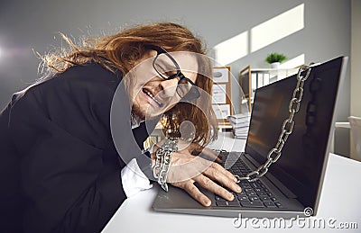 Side view of a tired crazy office worker who works overtime chained to a laptop and cries. Stock Photo