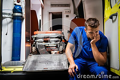 Corpsman sit on the ambulance car, put his head on hand and think Stock Photo