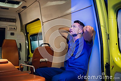 Corpsman sits inside the ambulance car and puts his hands on head and looks somewhere Stock Photo