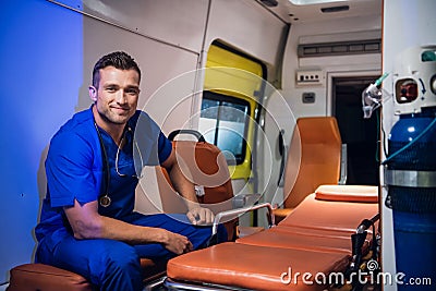 Corpsman in uniform sits in the ambulance car and smiles Stock Photo