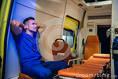 Corpsman in uniform sits inside the ambulance car and puts his hands on head and looks somewhere Stock Photo