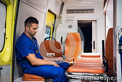 Corpsman in uniform sits inside the ambulance car and think Stock Photo