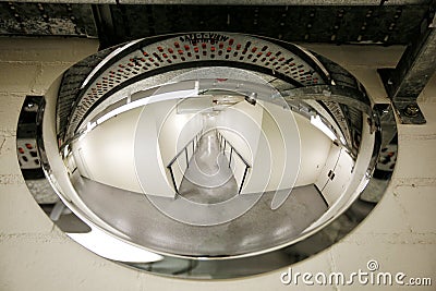 Corridor inside a building with blind corners and a convex saConvex safety mirror mounted on a wall opposite a blind corner of an Stock Photo