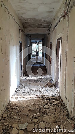 Corridor of ruined hotel with figure in the distance Stock Photo