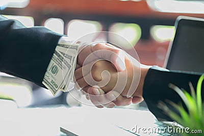 Corrupted businessman sealing the deal with a handshake and receiving a bribe money, anti bribery and corruption concepts Stock Photo