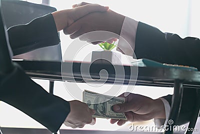 Corrupted businessman sealing the deal with a handshake and receiving a bribe money, anti bribery and corruption concepts Stock Photo