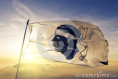 Corsica region of France flag textile cloth fabric waving on the top sunrise mist fog Stock Photo