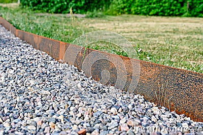 Corten steel as boundery between gravel and grass in garden Stock Photo