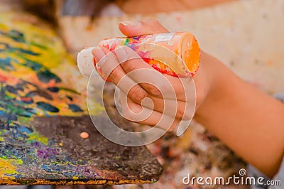 Cose up of woman hand with orange flask, over a color palette in a blurred background Stock Photo