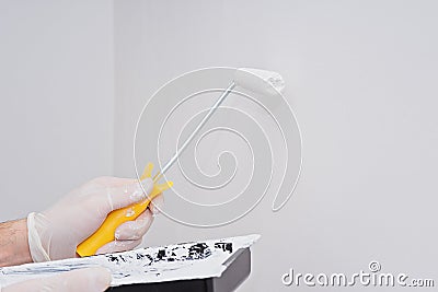 Coseup paint roller in hand with white paint on clean wall Stock Photo