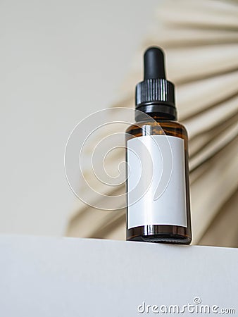 Cosmetic amber glass bottle with white lable down up on table and dry palm leaf on white background Stock Photo