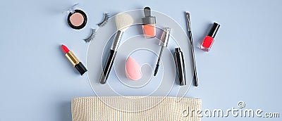 Cosmetic bag and make-up products on blue background. Beauty blog banner design. Flat lay, top view Stock Photo