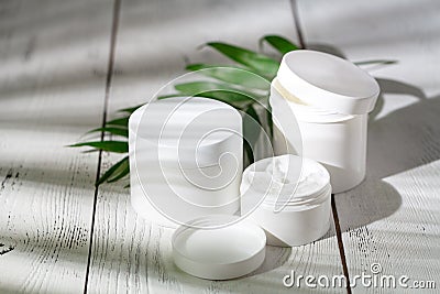 Cosmetic bottle containers with green herbal leaves, Blank label Stock Photo