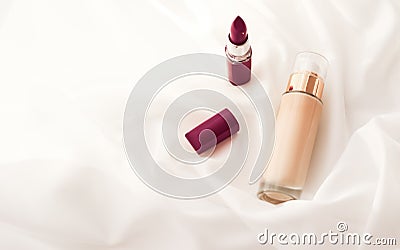 Beige tonal cream bottle make-up fluid foundation base and dark lipstick on silk background, cosmetics products as luxury beauty Stock Photo