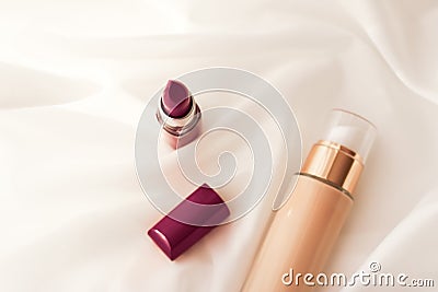 Beige tonal cream bottle make-up fluid foundation base and dark lipstick on silk background, cosmetics products as luxury beauty Stock Photo