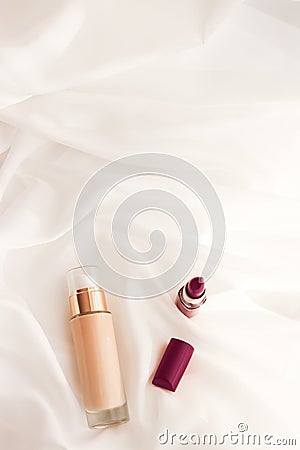 Beige tonal cream bottle make-up fluid foundation base and dark lipstick on silk background, cosmetics products as luxury beauty Stock Photo