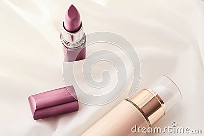 Beige tonal cream bottle make-up fluid foundation base and pink lipstick on silk background, cosmetics products as luxury beauty Stock Photo