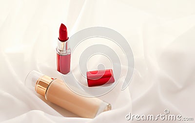 Beige tonal cream bottle make-up fluid foundation base and red lipstick on silk background, cosmetics products as luxury beauty Stock Photo