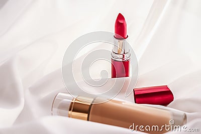 Beige tonal cream bottle make-up fluid foundation base and red lipstick on silk background, cosmetics products as luxury beauty Stock Photo