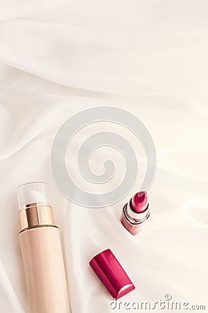 Beige tonal cream bottle make-up fluid foundation base and red lipstick on silk background, cosmetics products as luxury beauty Stock Photo