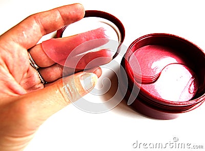 In a female hand a cosmetic patch for the face. Cosmetic eye patches in a jar on a white background. Face skin care. Modern Stock Photo