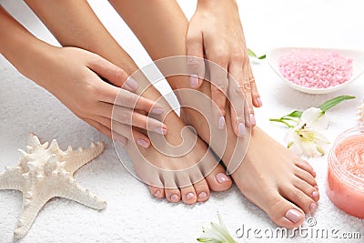 Cosmetic, flowers and woman touching her smooth feet on white towel, closeup. Stock Photo