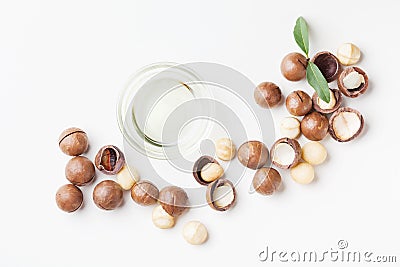 Cosmetic macadamia oil and heap of nuts on white table top view. Stock Photo