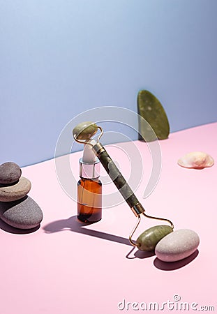 Cosmetic product in a glass bottle with a pipette and gua sha e scraper and roller. Smooth stones nearby. The concept of skin care Stock Photo