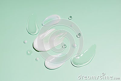 cosmetic smears cream texture on green background. Beauty serum drop. Transparent and creamy skin care product sample.. Stock Photo