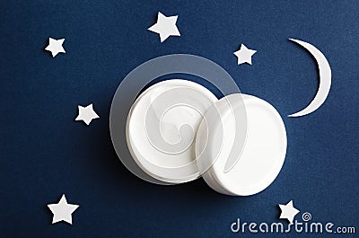 Cosmetic white container on night sky background top view. Skincare cosmetology product, night care concept. Organic cosmetics. Stock Photo