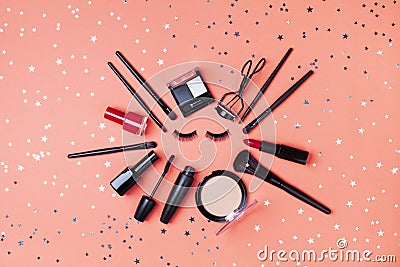 Cosmetic for woman makeup and beauty products decorated star confetti on coral table top view. Flat lay style Stock Photo