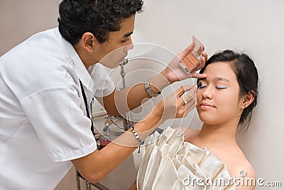 Cosmetician brushing face of Asian girl Stock Photo