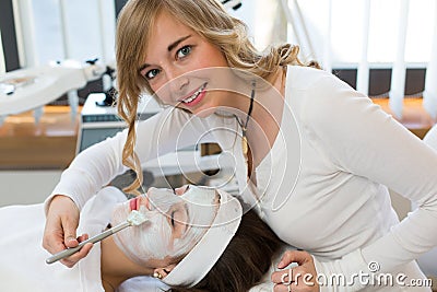 Cosmetician giving client facial skincare mask Stock Photo