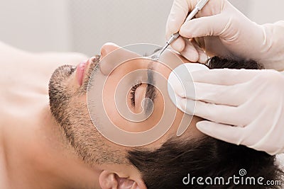 Cosmetician using blackhead remover for cleaning man face Stock Photo